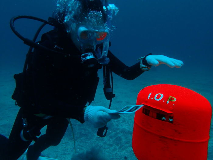 Underwater view of scuba diver posting letter in mailbox