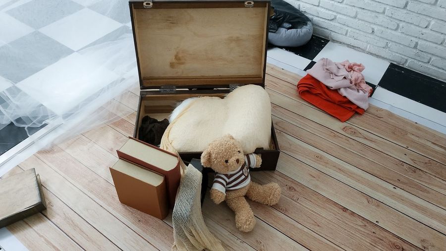 High angle view of teddy bear by suitcase on floor