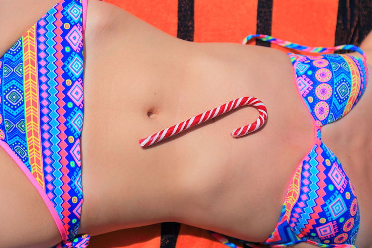 Midsection of sensuous young woman with candy cane
