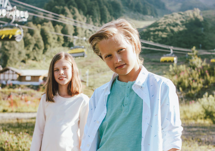 Portrait of siblings standing against mountain