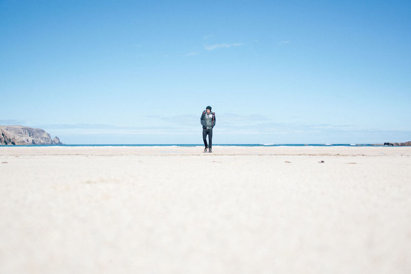 Full length of man standing at beach against sky