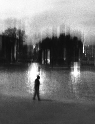 Silhouette person standing on road by lake in city at night