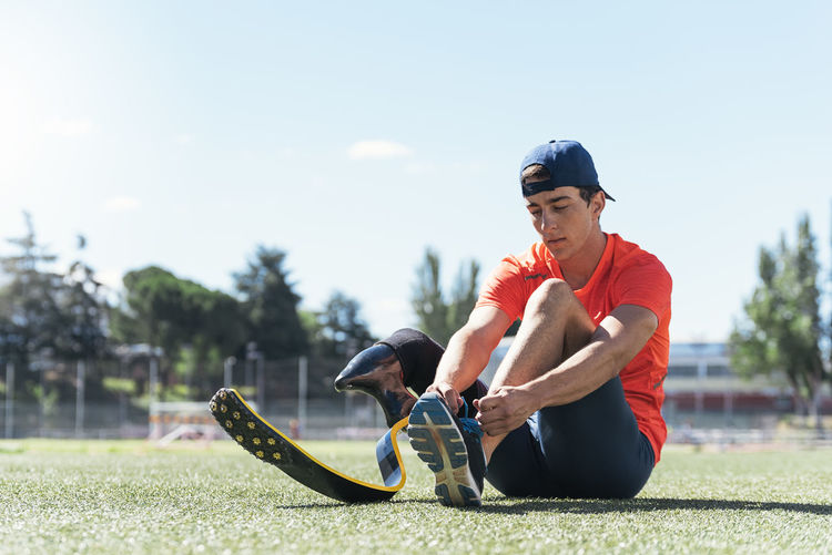 Man with prostethic leg sitting and tying shoes
