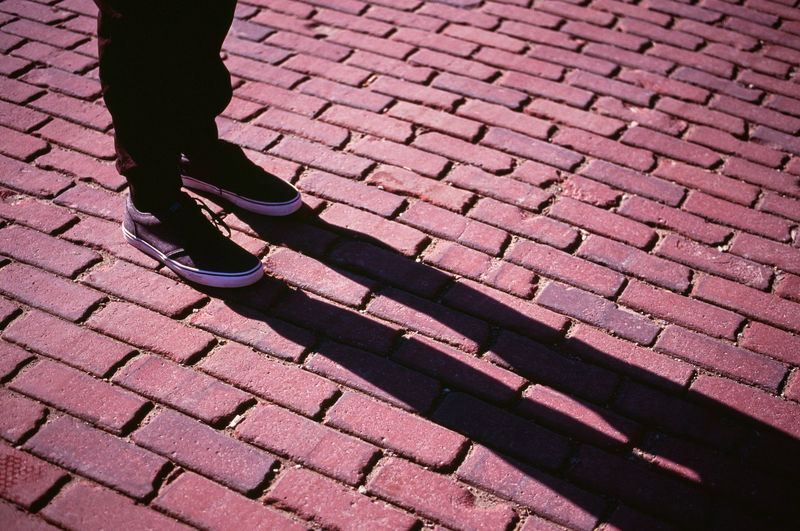 Low section of person standing on cobblestone street