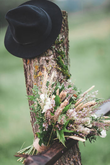 Close-up of bouquet and hat on wooden post