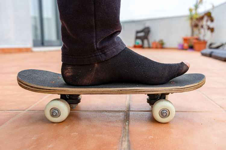 Low section of man standing on skateboard at home