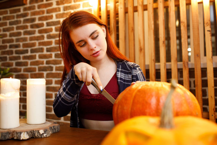 Portrait of young woman holding pumpkin on table