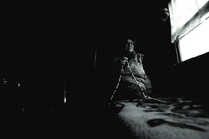 Senior woman praying by window in room