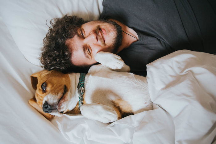 High angle portrait of man with dog on bed at home