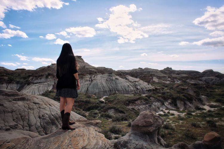 Rear view of woman standing on rock in badlands against sky