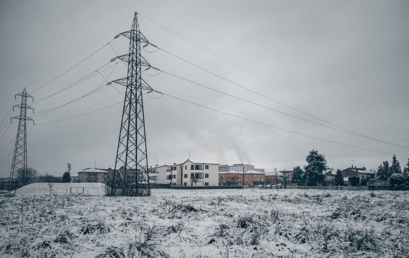 Electricity pylon on field against sky during winter