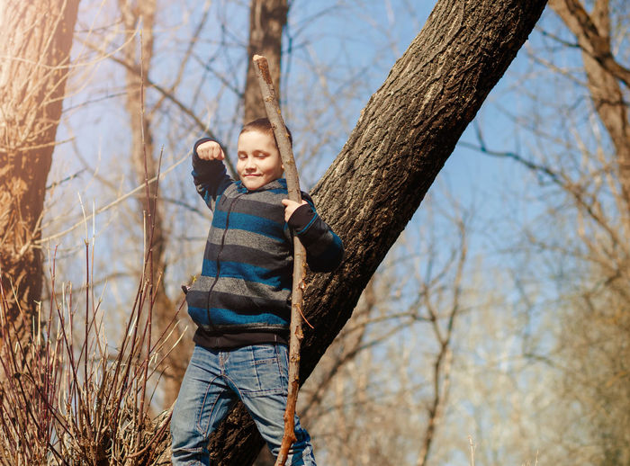 Happy boy standing on tree trunk