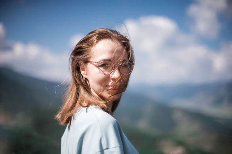 Portrait of woman standing on mountain against sky