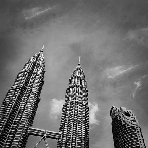 Low angle view of skyscrapers against cloudy sky