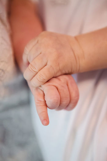 Hands of a newborn baby dressed in white