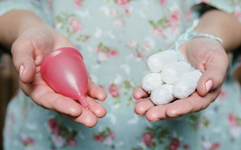 Midsection of woman holding tampon with menstrual cup