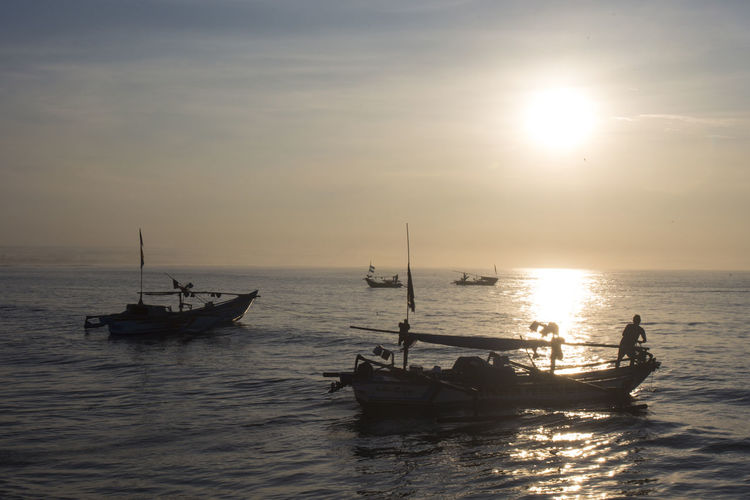 Scenic view of fishing boats during sunrise