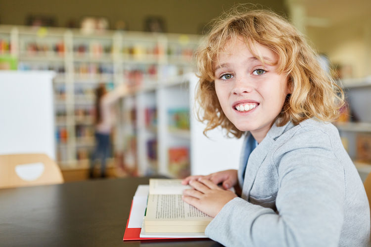 Portrait of smiling boy sitting with open book on table