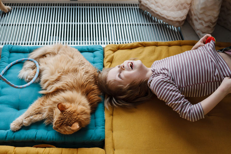 Happy smiling child resting on sports mats with his domestic sleeping cat. people and pets