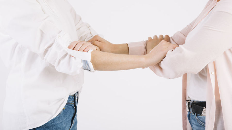 Midsection of doctor holding hands against white background