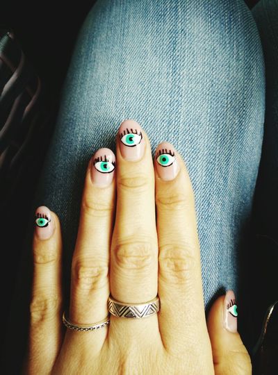 Close-up of human hand with eyes painted on nails
