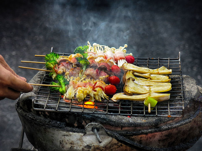 Cropped image of person cooking vegetables on barbecue grill