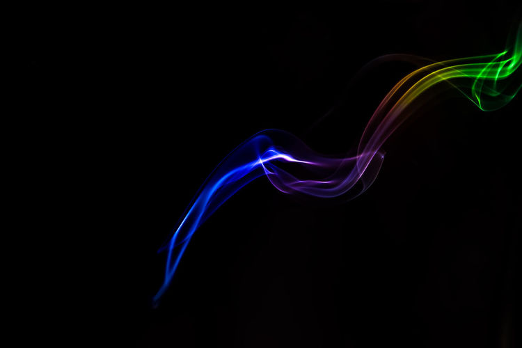 Close-up of multi colored smoke against black background