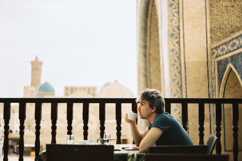Young man drinking coffee on the balcony in bukhara uzbekistan 