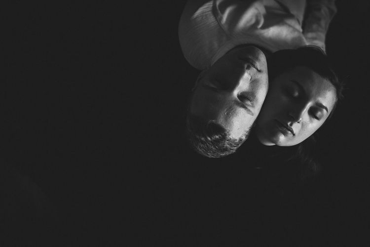 High angle view of couple with eyes closed on black background