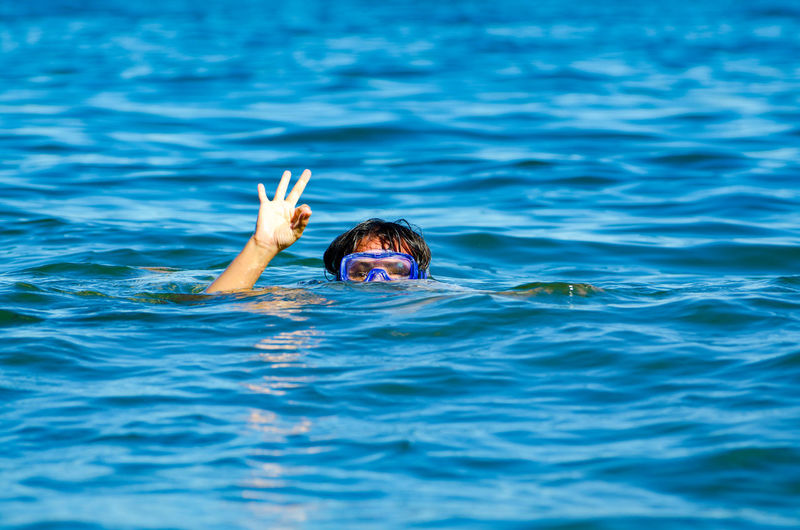 Woman gesturing ok sign while swimming in sea