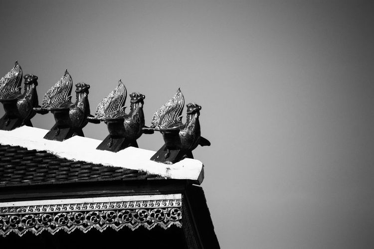 Low angle view of sculptures on roof of building against clear sky