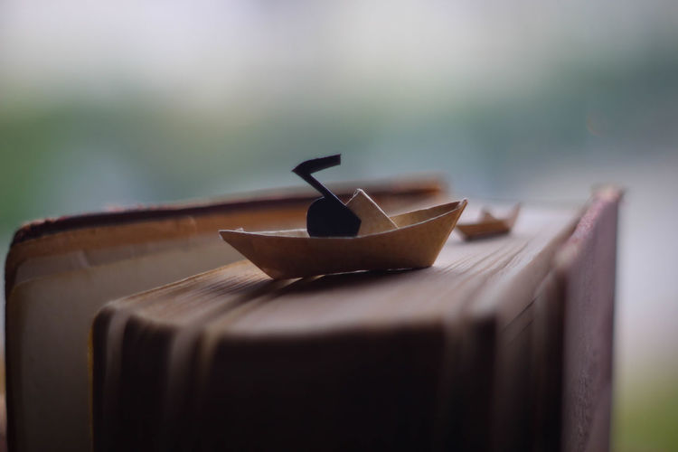 Close-up of origami ship on a book