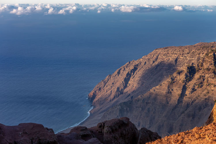 Scenic view of rocky mountains and sea against sky