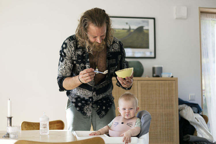 Man holding bowl and feeding baby son