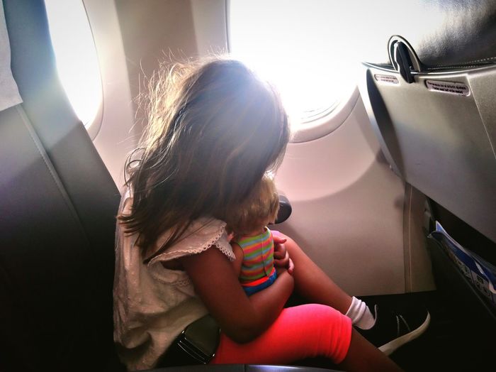 Rear view of girl sitting in airplane