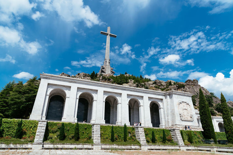 Low angle view of historical building and cross against blue sky