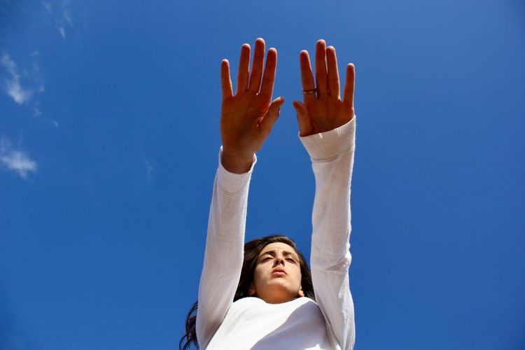 Low angle portrait of woman against blue sky