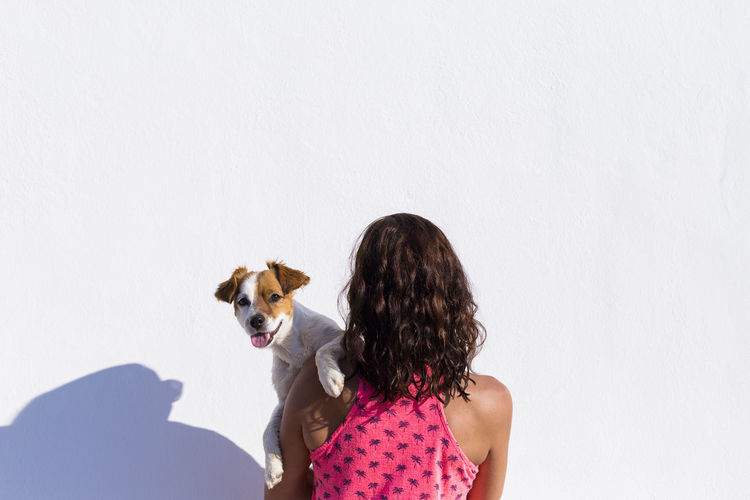 Woman with dog against wall