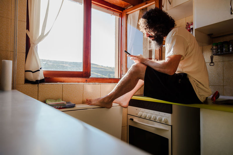 Man using mobile phone in kitchen at home