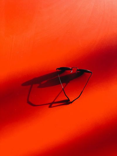 Close-up of eyeglasses on orange wall