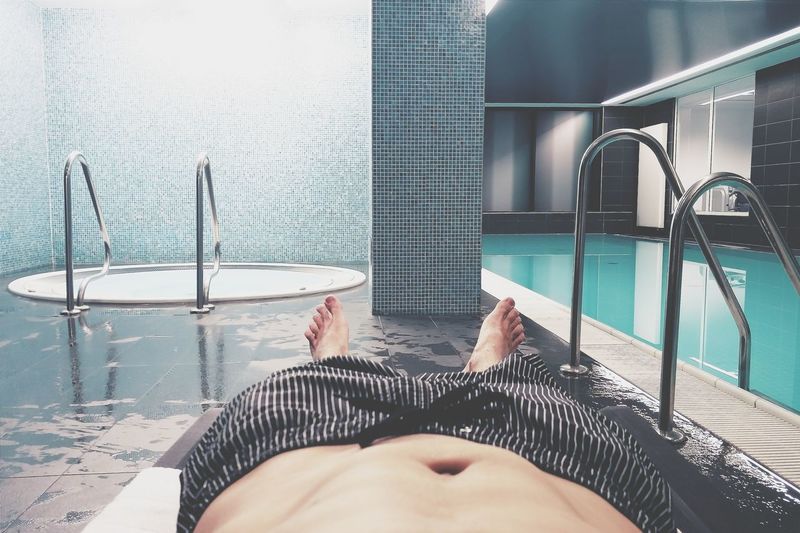 Low section of man lying at poolside in spa
