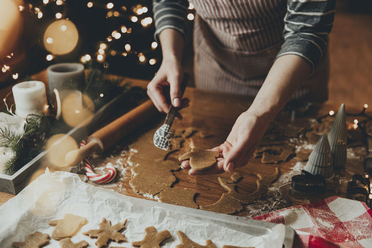 Young woman sculpts, cuts and carves gingerbread cookie figures from kneaded dough using forms