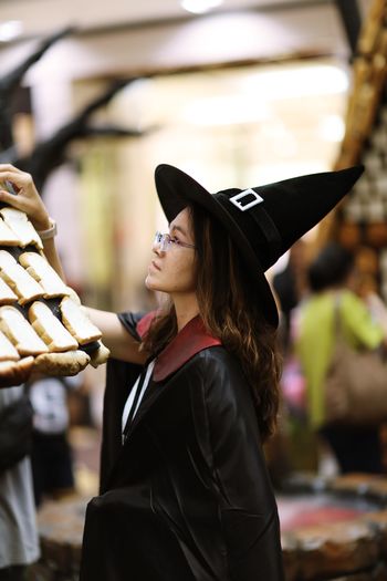 Side view of woman in witch costume arranging bread on house