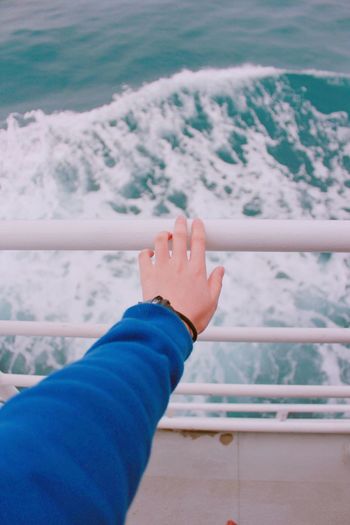Cropped hand touching railing at boat deck