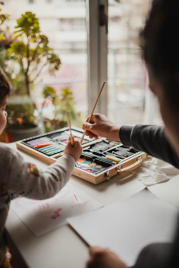 Mother and daughter painting on table