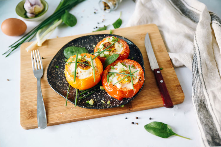Three large baked tomatoes with egg and herbs.