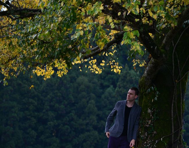 Thoughtful man standing by tree during autumn