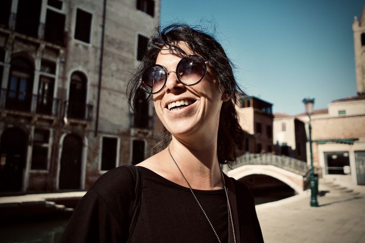 Portrait of smiling woman wearing sunglasses standing outdoors