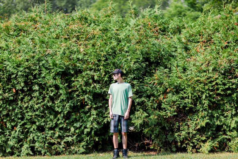 Full length of young man standing against plants