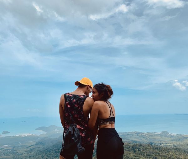 Couple romancing on mountain against sky